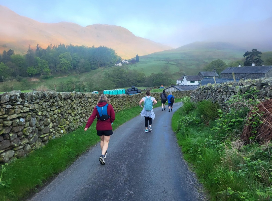 Walkers next to a stone wall with glowing morning light